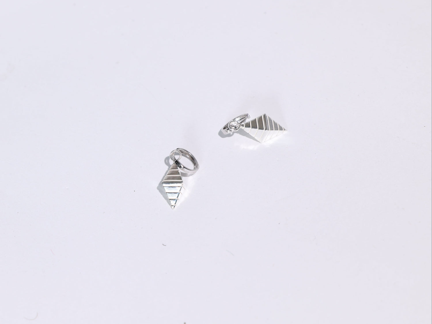 Pair of silver geometric earrings on a light gray background