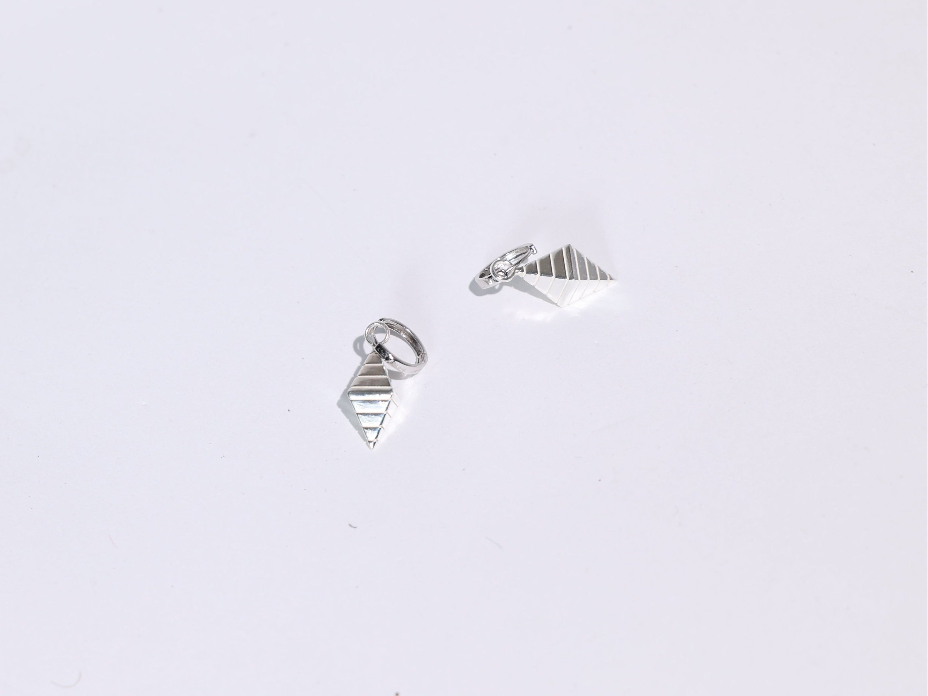 Pair of silver geometric earrings on a light gray background